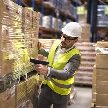 Male warehouse worker using bar code scanner to analyze newly arrived goods for further placement in storage department.